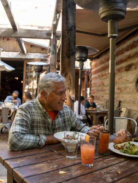 A man and a woman eating at a rustic restaurant patio with a cozy setting.