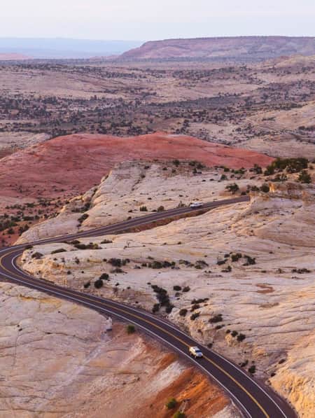 Expansive view of Utah's red rock landscape with Scenic Byway 12 winding through the terrain and two cars on the road.