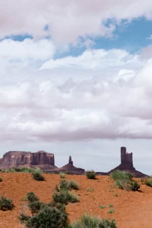 Two people hiking on a cloudy day along a path leading towards large monuments in the distance.
