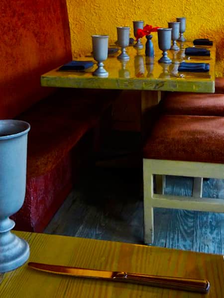 Wooden dining tables with napkins and silverware, and fabric-lined chairs at the Painted Pony Restaurant.