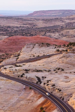 Expansive view of Utah's red rock landscape with Scenic Byway 12 winding through the terrain and two cars on the road.