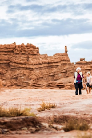 An adult and child hiking through the red rock formations at Goblin Valley State Park.