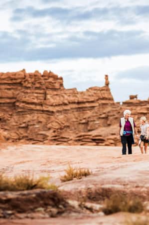 An adult and child hiking through the red rock formations at Goblin Valley State Park.