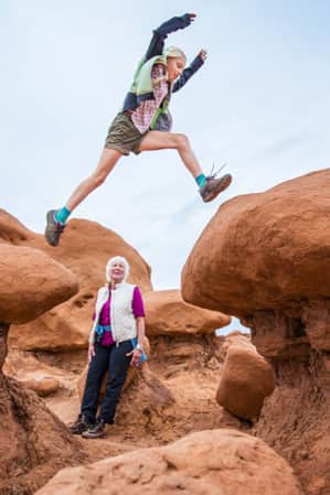 Young girl jumping across the goblins of Goblin Valley State Park.