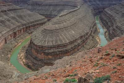 About 1,000 feet below the rim, the San Juan River has carved a deep canyon that loops around several tight bends called the Goosenecks.