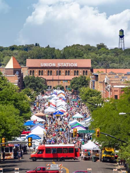 An overhead view of Ogden's downtown main street, bustling with crowds of people walking and exploring market tents set up along the road.