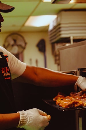 A man checking on barbecued meat in an industrial air fryer.