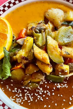 A colorful plate of sautéed vegetables in the center, with two sauces on either side of the plate.