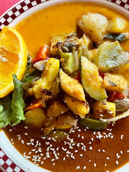 A colorful plate of sautéed vegetables in the center, with two sauces on either side of the plate.