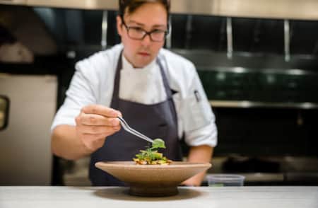 A chef adding the final garnish to a dish in a restaurant kitchen.