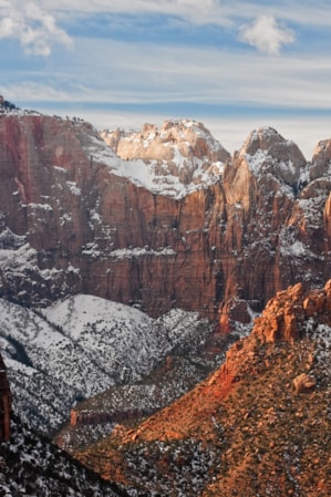 A valley surrounded by massive red rock cliff faces, lightly dusted with snow.