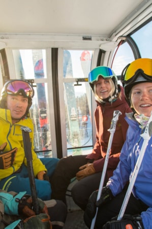 Four skiers riding inside a gondola, looking at the view in front of them.