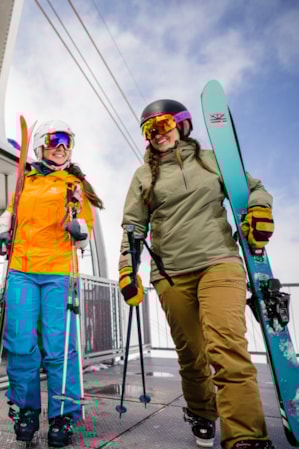 Three female skiers getting off a tram, holding their skis.
