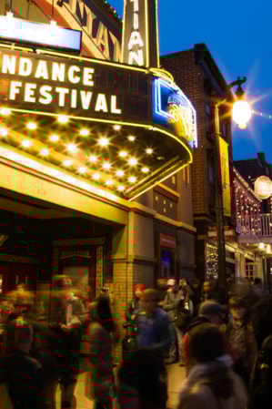 People standing outside a theater with illuminated lights.