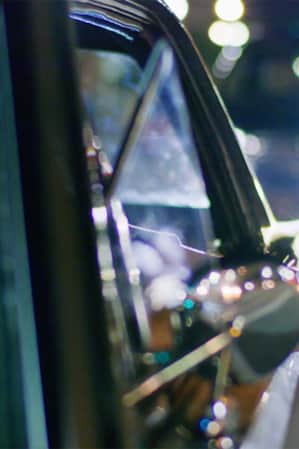 A man driving a vintage car at night.