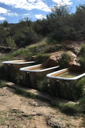 Three hot spring hot tubs built into the side of a rock.