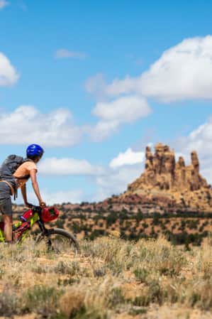 A woman bikepacking and looking at rock formations that resemble tall towers.