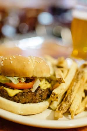 A hamburger and a side of French fries, served on a white plate.