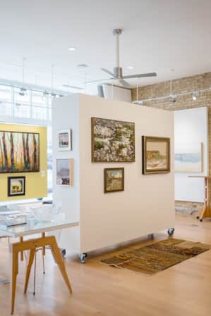 A gallery with abundant natural lighting showcasing art depicting nature scenes.