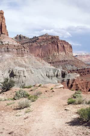 A sandy trail set against large red rock formations in the desert.