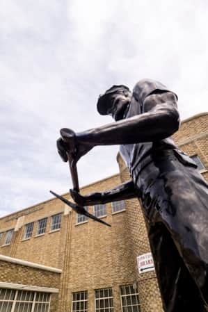 A metal statue of a railroad worker located in front of a library.