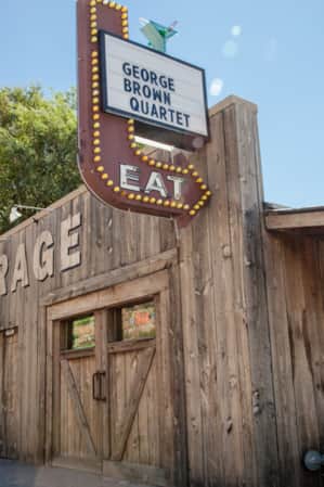 A wooden building with a sign featuring an arrow pointing to the front door that reads "Eat."