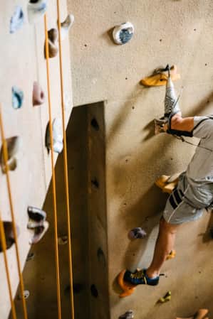 A person rock climbing on an indoor climbing wall.