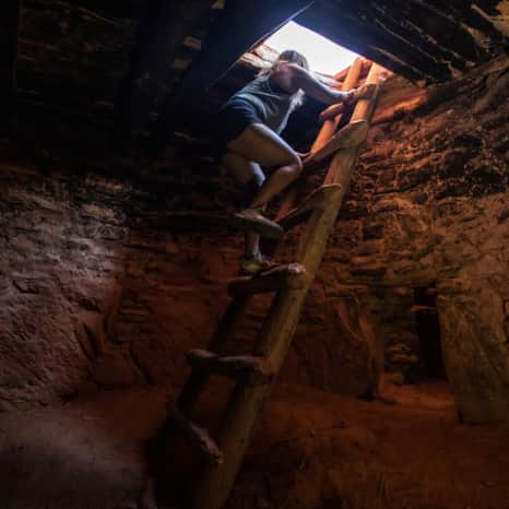 Climbing up and out of the Defiance House, one of the most famous and best-preserved Ancestral Puebloan dwellings located in Forgotten Canyon.