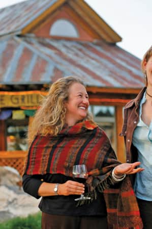 Two women facing the camera, candidly smiling in front of a restaurant.