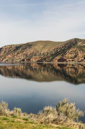 Blue skies at Echo Reservoir with the hills in the backdrop reflecting in the water.