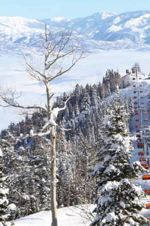 Skiers and snowboarders on ski lifts at Canyons Ski Resort in Park City, surrounded by snow-covered mountains.