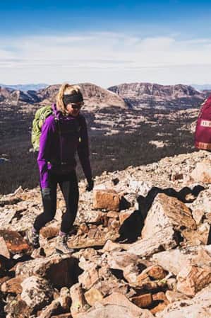 Two women hiking uphill through rocky terrain.