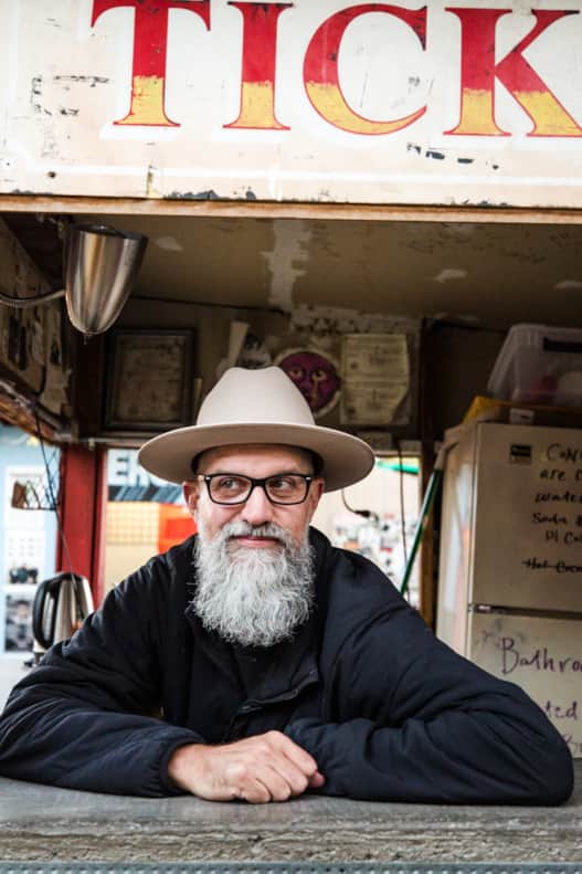 Beard recently trimmed and scented with bay leaf and tobacco, Brad Wheeler takes a shift behind the ticket counter