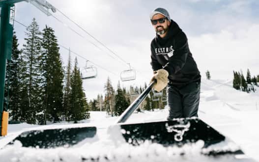 Mouse, terrain park designer and head digger, shovels out snow for a newly-placed rail at Brighton Ski Resort.