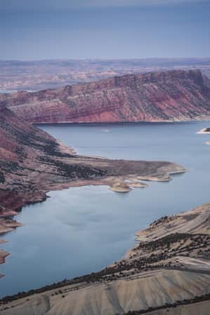 An aerial view of a wide canyon leading into a body of water, which connects to a larger lake.