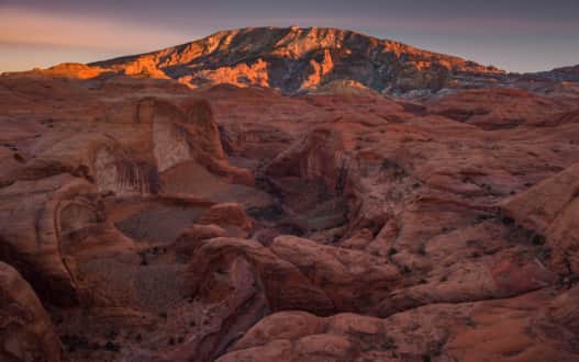 A beautiful view of Rainbow Bridge with Navajo Mountain illuminated in the distance.
