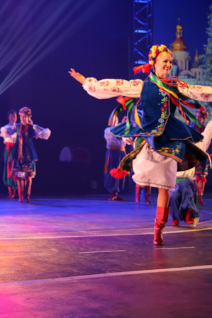 Performers on a stage in costumes, dancing.