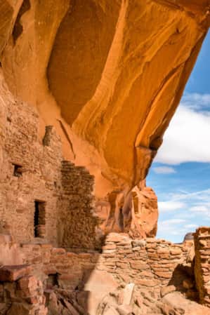 Ruins built into the side of a large red rock feature.