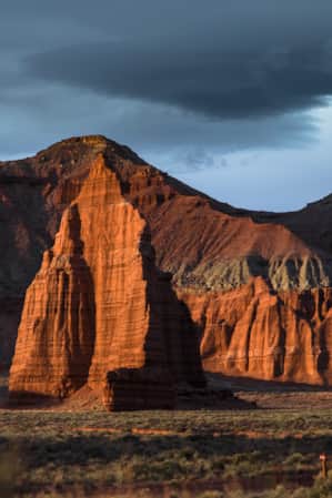 A cliff face of a rocky mountain range, illuminated by the setting sun.