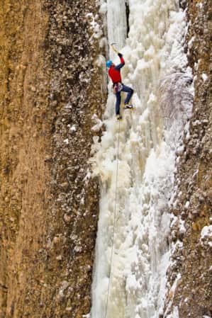 A climber ice climbing on a frozen waterfall.
