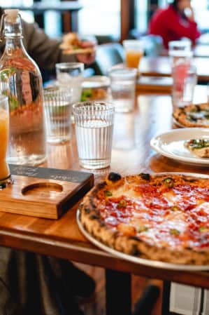 People sitting at a table, sharing and enjoying multiple pizzas.