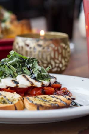 A plate of bruschetta with nachos in the background.