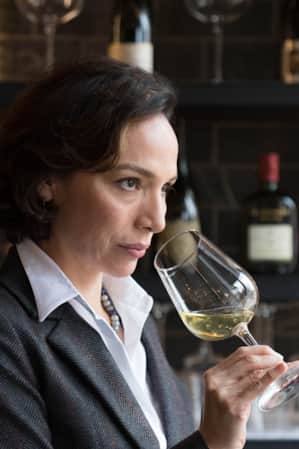 A woman holding a wine glass near her nose, smelling the aroma.