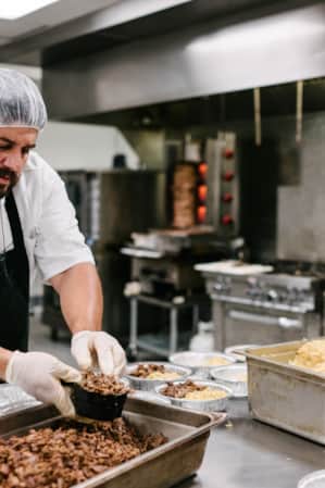 A cook preparing pre-made meals in an industrial kitchen.