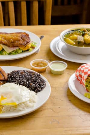 A wooden table with four plates of food arranged on it.