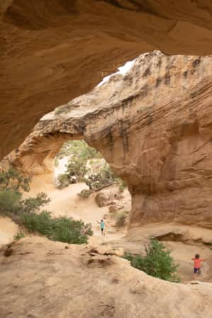 A family exploring a large rock formation with multiple arches they can walk under.