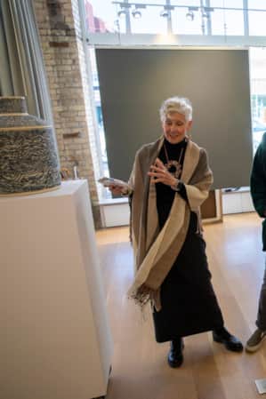 Two women in an art museum, smiling and discussing a piece of artwork.