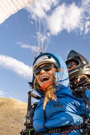 A man and a woman skydiving together, both screaming as they fall through the sky.