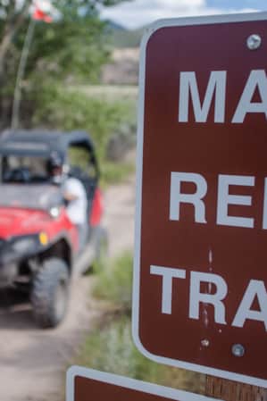 A sign reading 'Max Reid Trail' next to a person driving a red ATV.