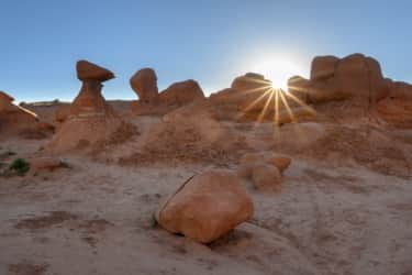 By day, red rock sandstone formations at Goblin Valley State Park contrast starkly against bright blue skies.